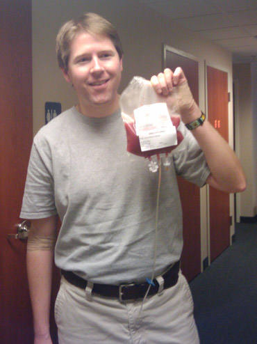 A man in a hospital holding a blood bag with stem cells